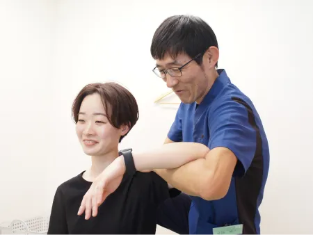 女性患者の肩を施術している男性施術者の様子