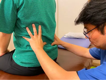 座位で腰の施術を行う整体師の様子
